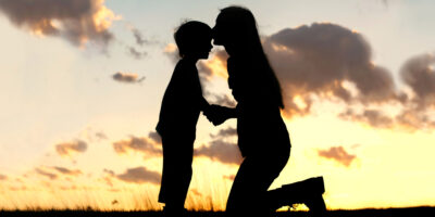 Silhouette of mother kissing her son on the head