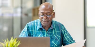 A man reviewing paperwork at his computer.