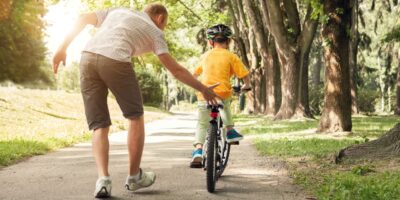 A father teaching a child to ride a bike.